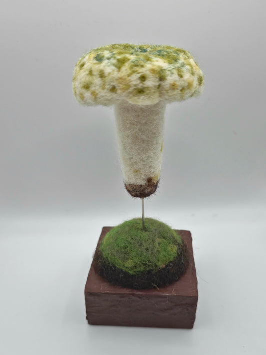 Textured mushroom sculpture on a brown base against a white background