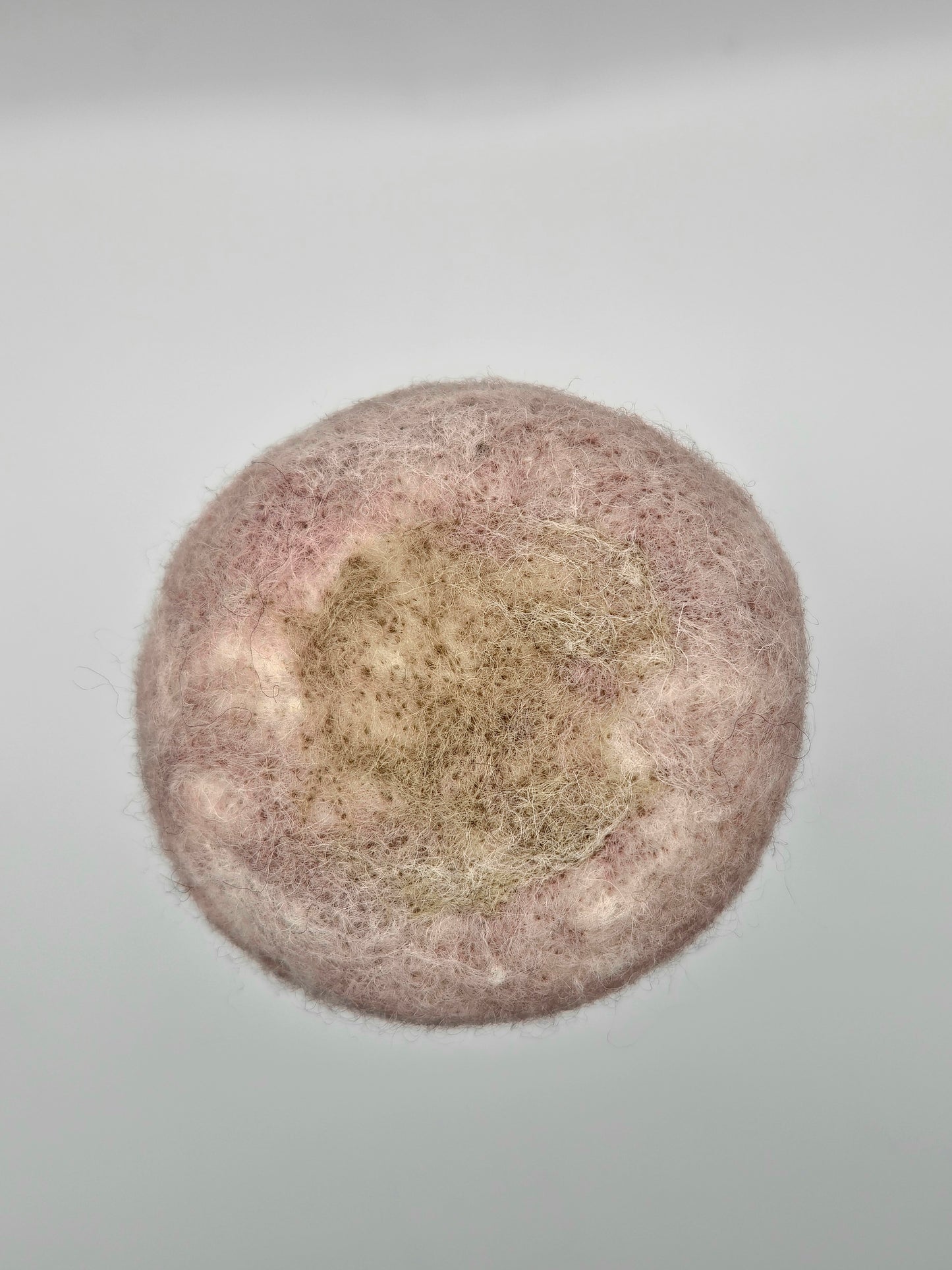 Round brown and green needle felted shape on white background