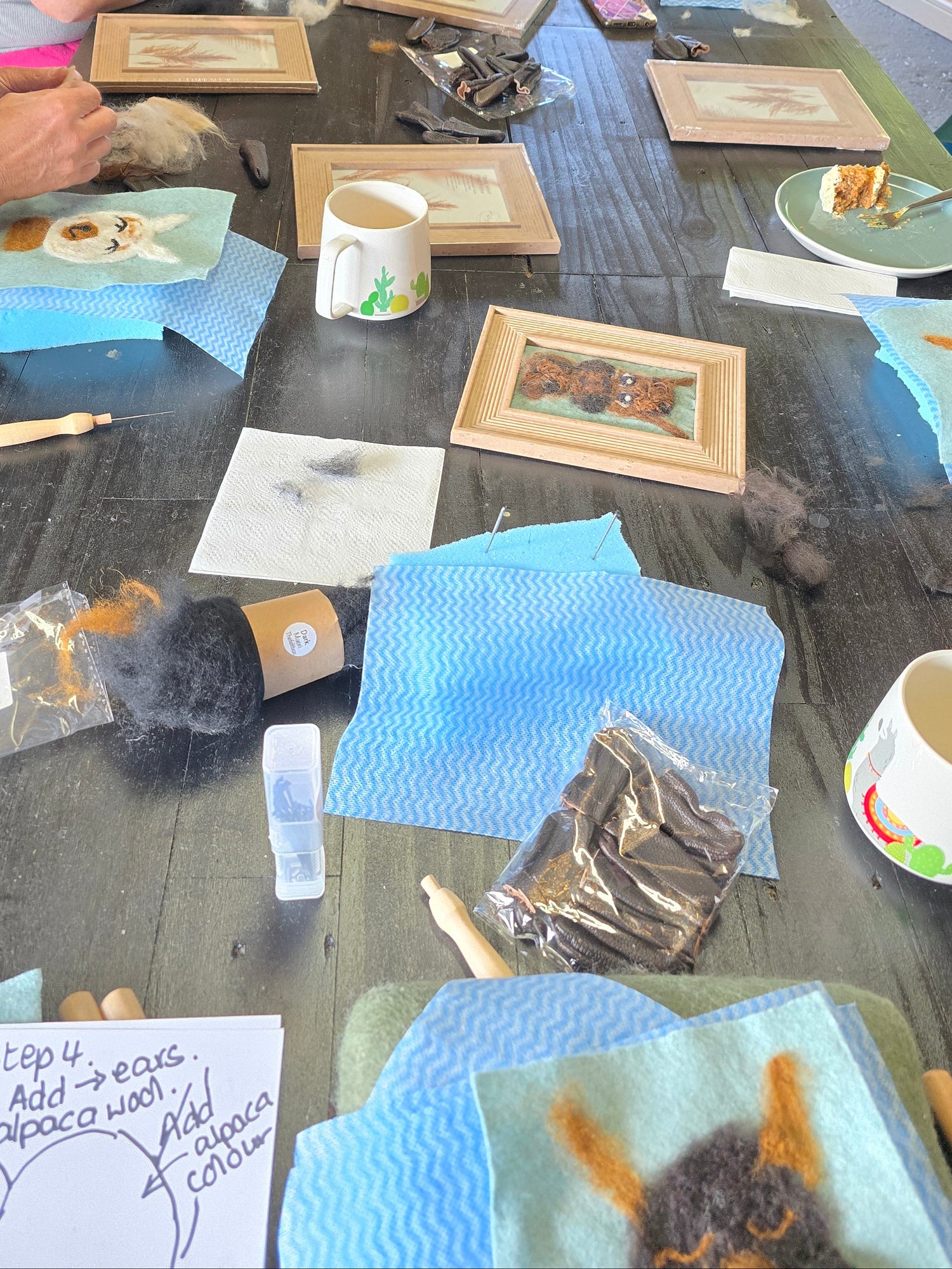 People working on a craft project at a table with various materials and tools.