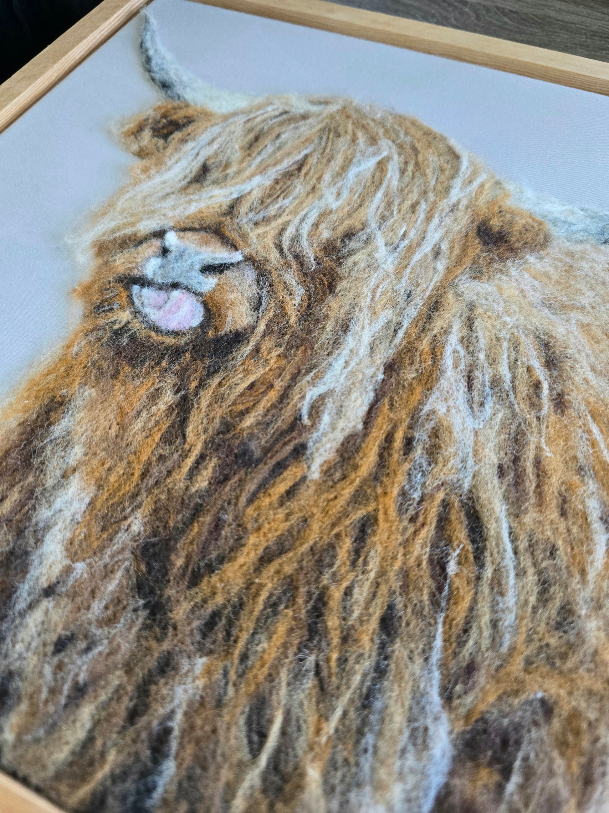 Close-up of a needle felted design of a highland cow's face.