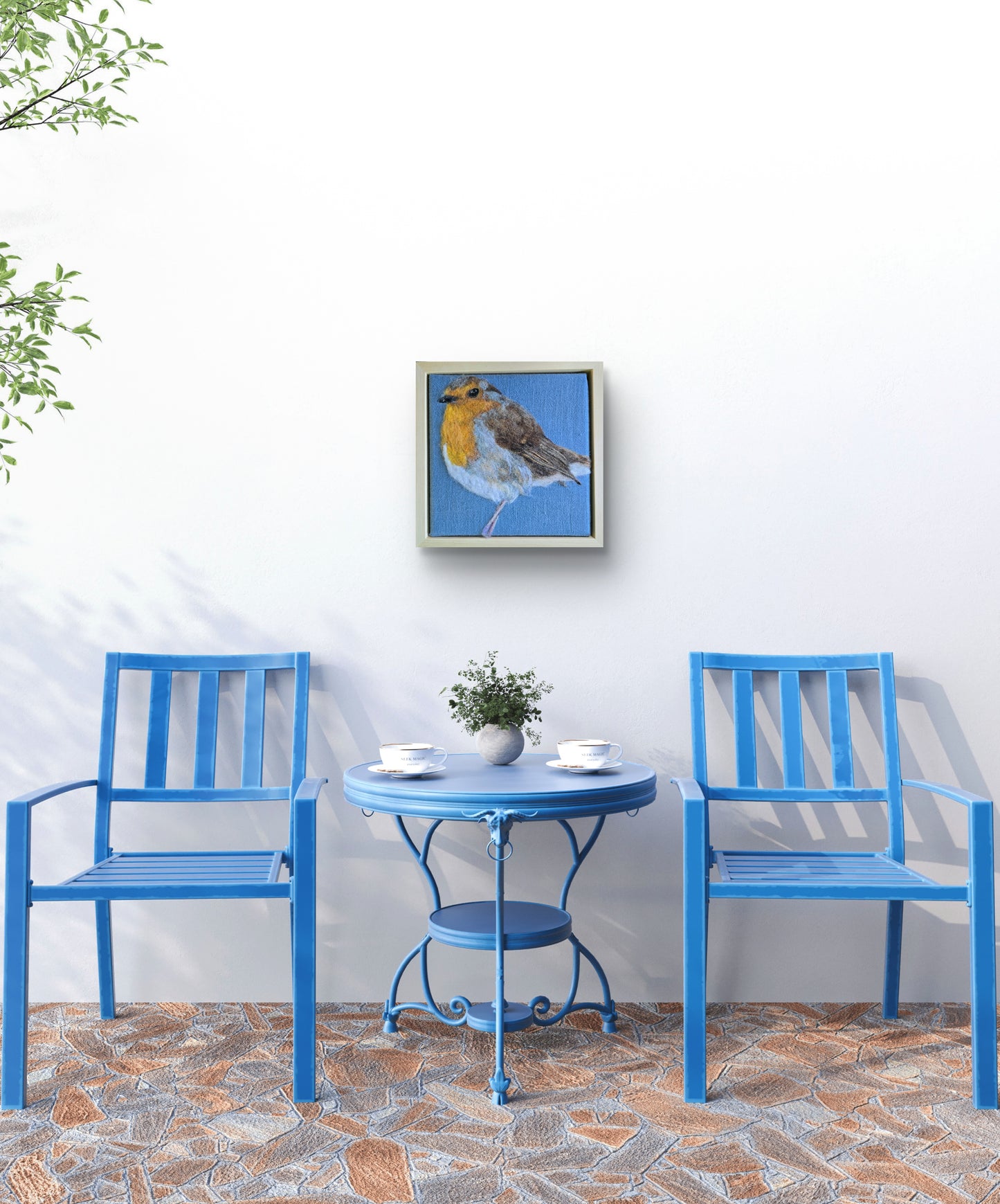 Blue chairs and table set against a white wall with a framed picture of a bird.