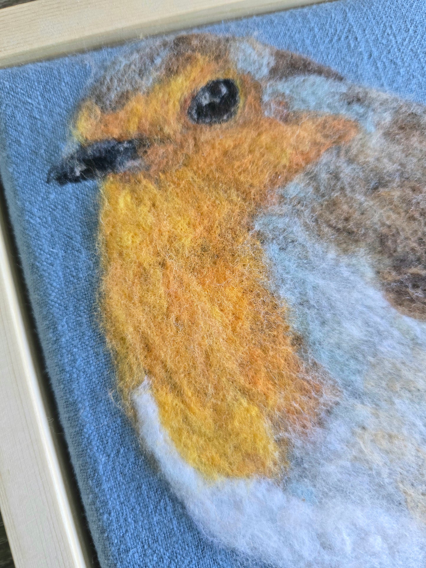 Needle felted artwork of a robin on a blue background